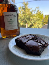 a white plate with a brownie and a bottle of whisky